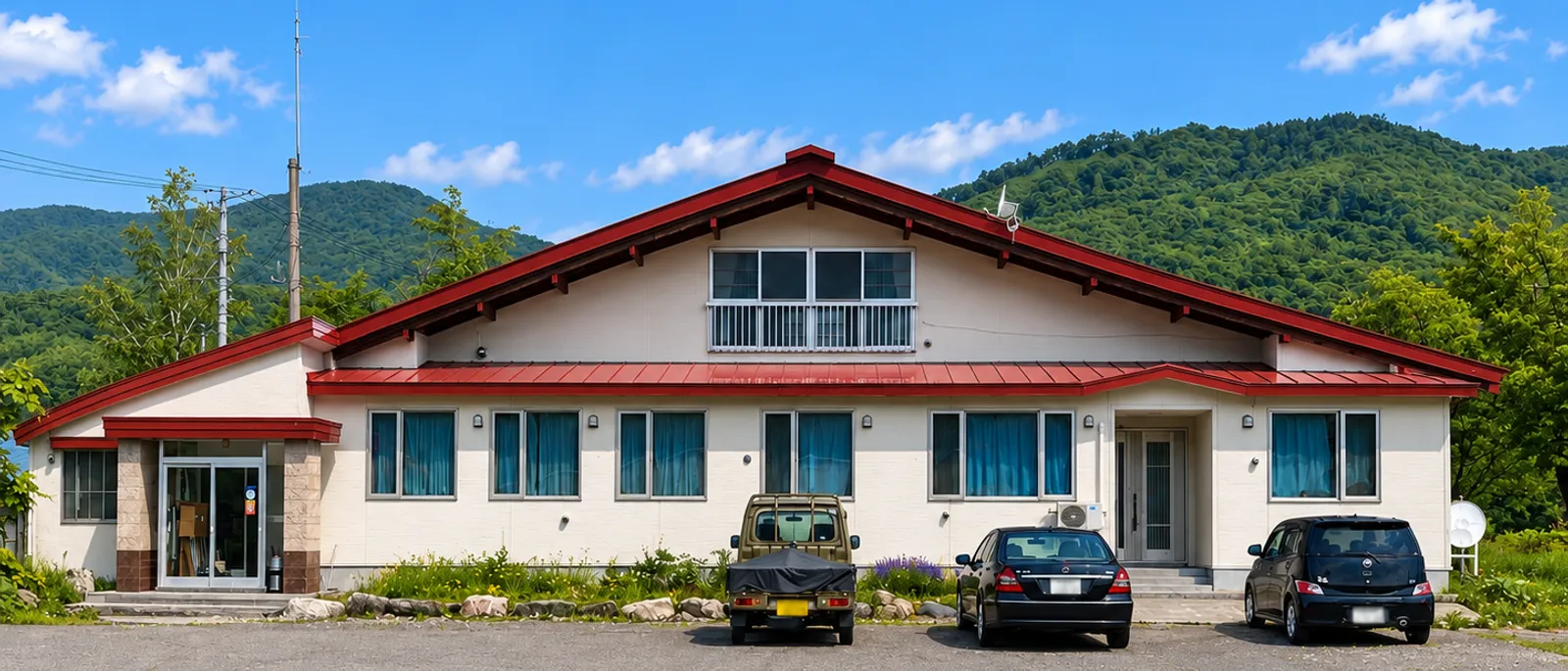 株式会社矢木組の社屋。赤い屋根の建物と、背後に広がる山並み